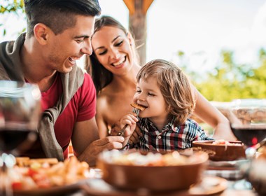 Cheerful young father feeding his son in restaurant.jpg